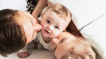 Blick von oben auf eine Baby, das von Mutter und Vater geküsst wird