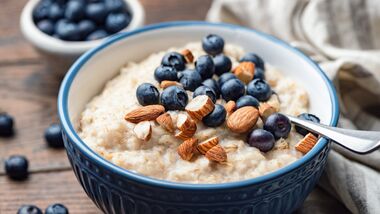 Bowl of homemade oatmeal porridge with banana, blueberries and almonds