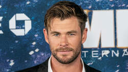 Chris Hemsworth trägt ein Jacket und ein offenes Hemd bei einer Präsentation eines Films.