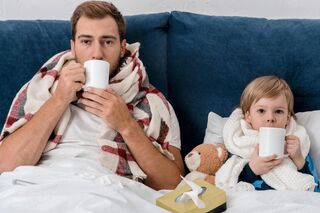 Ein Vater und sein Sohn liegen krank im Bett
