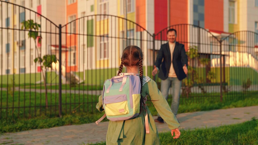 Ein Vater wartet vor dem Schulgelände auf seine Tochter