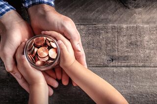 Kinderhände übergeben ein Glas mit Kleingeld an erwachsene Hände