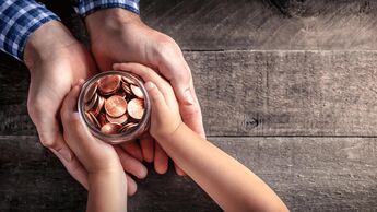 Kinderhände übergeben ein Glas mit Kleingeld an erwachsene Hände