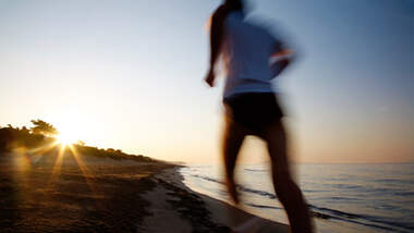 Läufer am Strand beim Sonnenuntergang