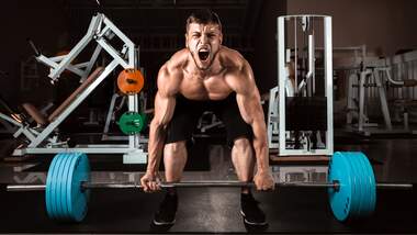 Mann beim Deadlift rinkt sichtbar nach Kraft