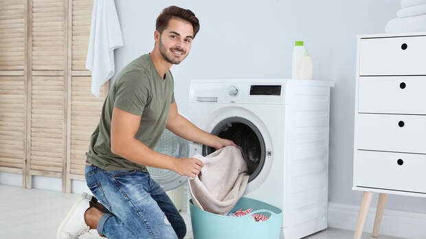 Mann füllt Waschmaschine