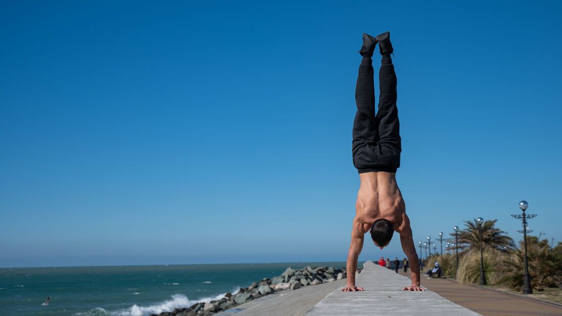 Shirtless,Man,Doing,A,Handstand,On,The,Seashore.