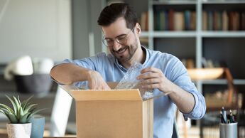 Smiling,Man,Wearing,Glasses,Unpacking,Awaited,Parcel,,Looking,Inside,,Sitting