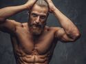 Trainierter Mann mit Bart post mit freiem Oberkörper 