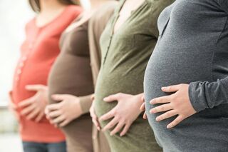Vier schwangere Frauen, die ihre Hände auf den Bauch gelegt haben