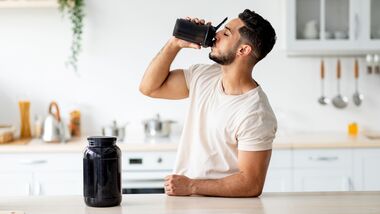Young,Arab,Guy,Drinking,Protein,Shake,From,Bottle,At,Kitchen,