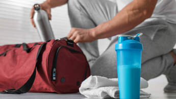 Young,Man,Putting,Bottle,Of,Water,Into,Bag,Indoors,,Focus