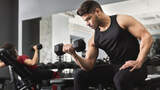 junger, athletischer Mann trainiert seinen Bizeps im Gym